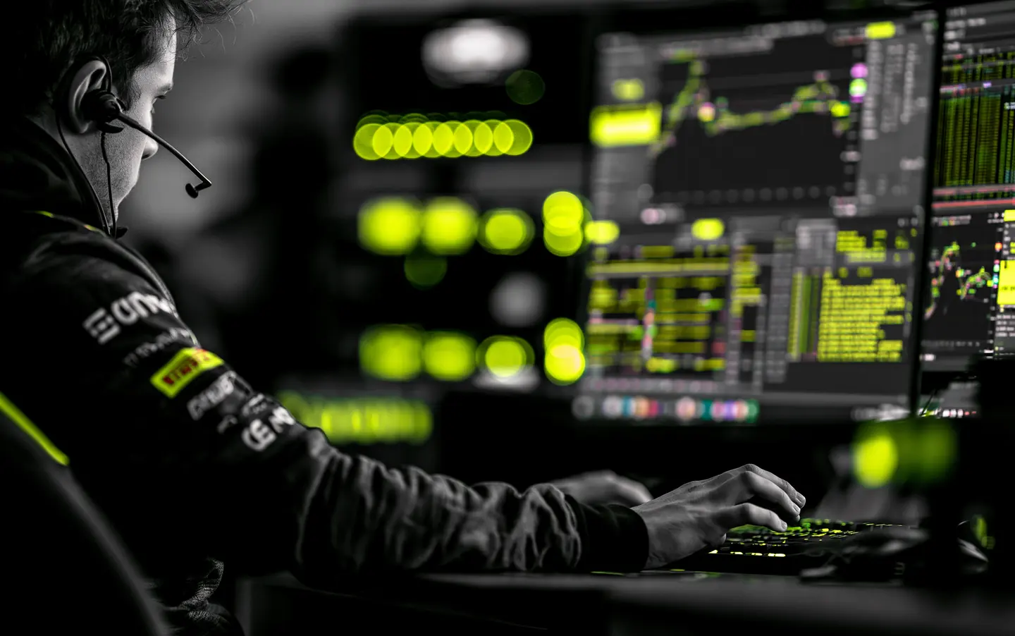 Race engineer studying telemetry while reaching across a workstation